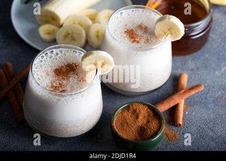 Banana Smoothie mit Zimt in Gläsern mit Früchten auf Stein Hintergrund. Stockfoto