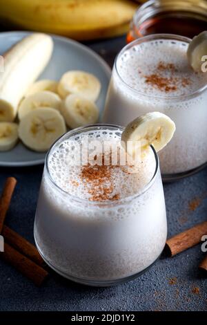 Banana Smoothie mit Zimt in Gläsern mit Früchten auf Stein Hintergrund. Stockfoto