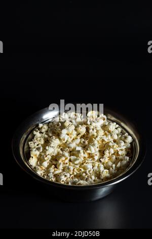 Portion Popcorn im Eimer auf schwarzem Hintergrund, mit Copyspace. Stockfoto