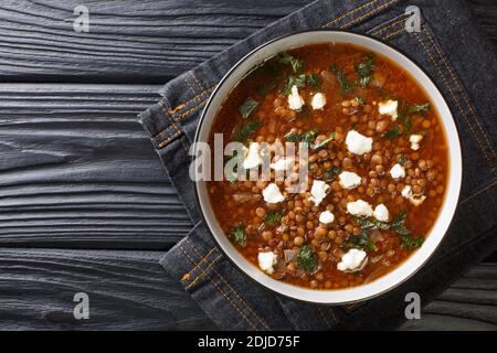 Griechische traditionelle Linsensuppe mit Feta, Essig und Olivenöl aus der Nähe auf einem Teller auf dem Tisch. Horizontale Ansicht von oben Stockfoto