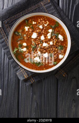 Vegetarische, traditionelle griechische Suppe mit Linsen, die in der Nähe auf einem Teller auf dem Tisch serviert wird. Vertikale Draufsicht von oben Stockfoto