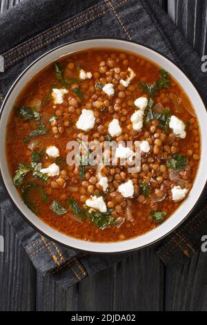 Gefälscht griechische Linsensuppe serviert mit Feta close-up in einem Teller auf dem Tisch. Vertikale Draufsicht von oben Stockfoto