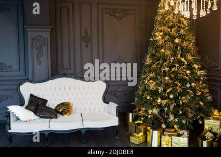 Das Velorsofa im dunklen Raum mit dekorierten Weihnachten Baum und goldene Geschenkschachteln Stockfoto