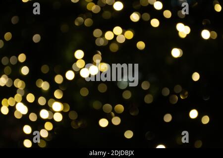 Abstrakter Hintergrund gelb Bokeh Lichter und Zweige eines Baumes im Winter, Weihnachten oder Party-Hintergrund, gemütlich und warm Gefühle Stockfoto