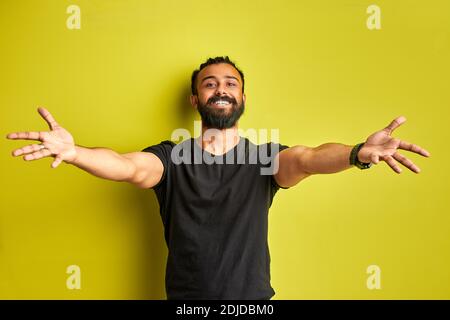 Lassen Sie uns umarmen Sie. Junge positive Mann mit ausgebreiteten Armen Blick auf Kamera, isoliert auf grünem Hintergrund Stockfoto