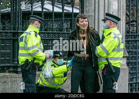 WESTMINSTER LONDON 14. Dezember 2020. Ein Protestler wird nach der Verhaftung durch die Polizei während eines Anti-Lockdown-Protests von Stand-up X in Westminster mit Handschellen gefesselt, während London sich darauf vorbereitet, in den nächsten Tagen in eine hohe Sicherheitswarnung mit härteren Restriktionen zu ziehen. Kredit: amer ghazzal/Alamy Live Nachrichten Stockfoto