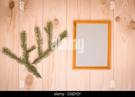 Mock up leere Holzrahmen und Tannenzweige auf azurblauem Kiefernholz Wand Hintergrund, Text oder Produkt zeigen. Weihnachtsthema. Stockfoto
