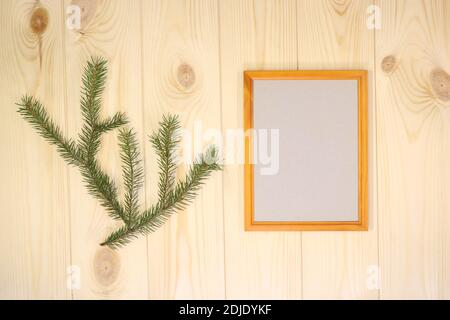 Mock up leere Holzrahmen und Tannenzweige auf azurblauem Kiefernholz Wand Hintergrund, Text oder Produkt zeigen. Weihnachtsthema. Stockfoto