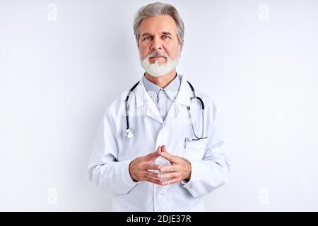 Selbstbewusst ältere männliche Arzt in weißen medizinischen Uniform mit Stethoskop, schaut auf Kamera posiert, isoliert auf weißem Hintergrund. Medizin Konzept Stockfoto