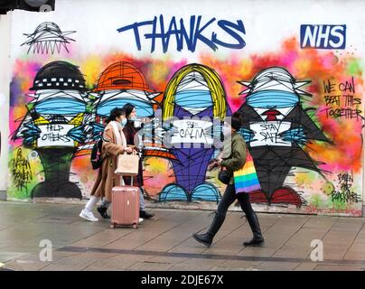 Shopper in der Londoner Oxford Street gehen an einem Kunstwerk vorbei, das maskierte Menschen zeigt und die Arbeit des NHS lobt. Stockfoto