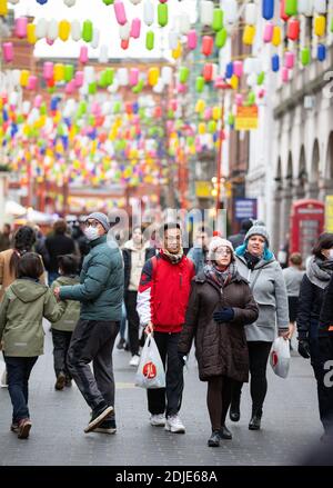 Menschen, die durch Chinatown im Londoner West End spazieren. Die Straße liegt im Zentrum der pulsierenden chinesischen Gemeinde mit vielen Restaurants und Bars. Stockfoto