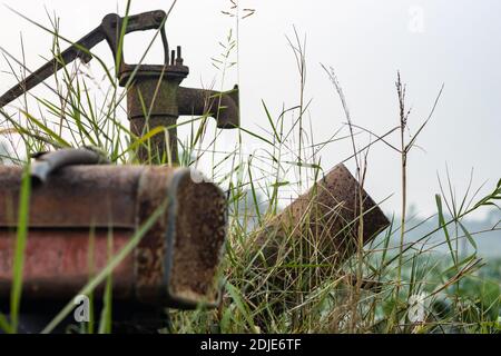 Eine nutzlose rostige Wasserpumpe im landwirtschaftlichen Feld im Inneren Die wilden Gräser Stockfoto