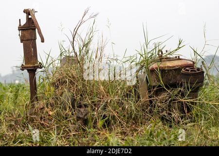 Eine alte rostige nutzlose Wasserpumpe im Gras hinein Die landwirtschaftliche Fläche in der ländlichen Dorf Stockfoto