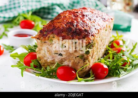 Leckere hausgemachte Hackbraten aus gemahlenem Huhn mit grünen Erbsen und Brokkoli in Scheiben auf weißem Tisch. Essen american Meat Laib Stockfoto
