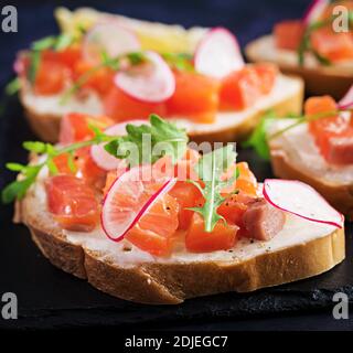 Sandwich mit gesalzenem Lachs für gesundes Frühstück auf dunklem Hintergrund. Fischmenü. Stockfoto