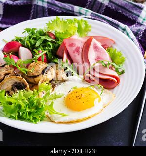 Englisches Frühstück - Spiegeleier, Schinken, gebratene Pilze, Rettich und Rucola. Ketogen, Keto-Essen. Stockfoto