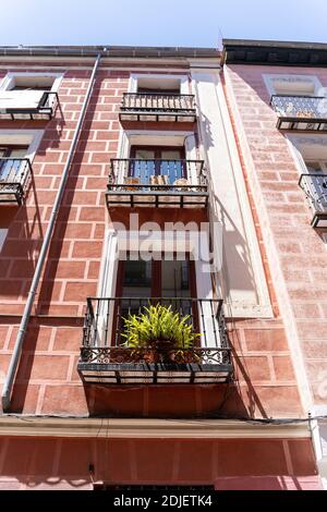 Fassade der roten Wohnwohnung mit Blumen und Balkonen in Madrid Stockfoto