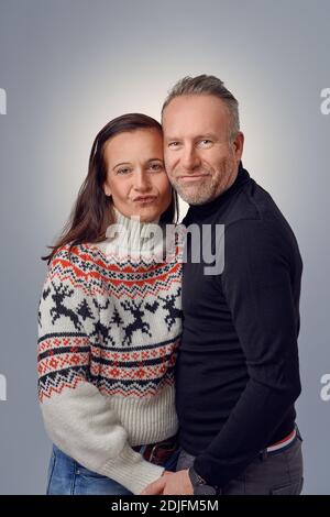Ein glückliches Paar mittleren Alters lachte und umarmte sich gegenseitig mit einem weihnachtsmütze und ein Elchband Stockfoto