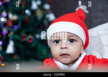 Portrait of Baby im Weihnachtsmann Kostüm mit Baum im Hintergrund Stockfoto