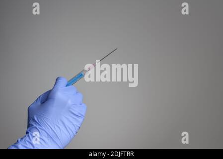 Arzthand in blauen Schutzhandschuhen mit Spritze Stockfoto