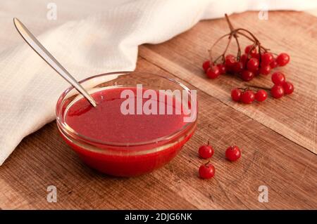 Rote Beeren des Viburnums, gemahlen mit dem Zucker in der Glasvase auf dem hölzernen Tisch. Vitaminsüße. Stockfoto