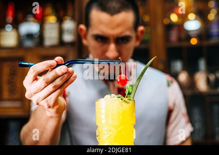 Der Barkeeper bringt eine Kirsche auf einen Tiki-Cocktail Stockfoto