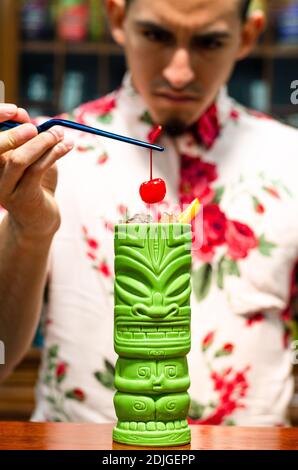 Der Barkeeper bringt eine Kirsche auf einen Tiki-Cocktail Stockfoto