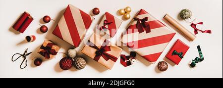 Flaches Lay von festlichen Geschenkschachteln, Geschenkpapier, bunte Kugeln, Bänder auf weißem Hintergrund, Draufsicht. Weihnachten Urlaub trendy Grußkarte, Banner. Weihnachtsfeiertag Stockfoto