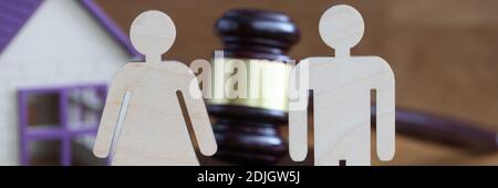 Holzfiguren von Mann und Frau, die auf dem Tisch in der Nähe stehen Richter Hammer und Spielzeughaus Nahaufnahme Stockfoto