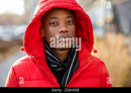 Junger Mann mit Kapuze und Blick auf die Kamera im Freien Stockfoto