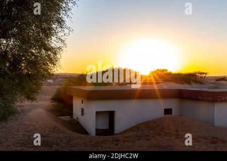 Al Madam Geisterstadt Landschaft, Wohngebäude in Sanddünen begraben, durch Sonnenuntergang beleuchtet. Stockfoto