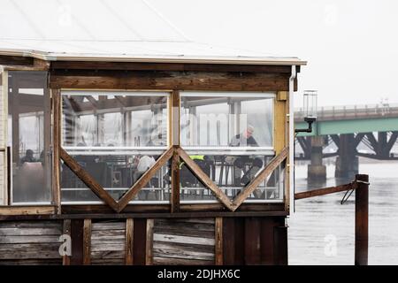 Gäste saßen an einem Wintertag auf der Terrasse des Tuscan Sea Grill and Bar am Merrimack River in Newburyport, Massachusetts, USA. Stockfoto