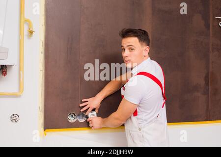 Der junge Elektriker, der in einem neuen Gebäude arbeitet Stockfoto