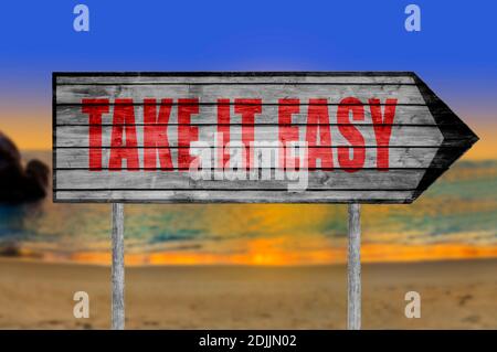 Rot Take IT Easy Holzschild mit am Strand Hintergrund Stockfoto