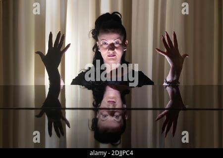 Elegant Italian Woman pianist showing hands above a black grand piano Stock Photo