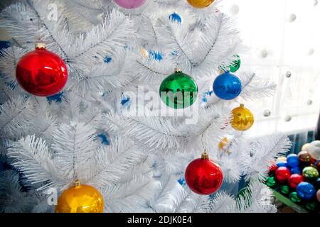 Weißer Weihnachtsbaum mit farbigen Weihnachtskugeln und einem verziert Box mit Kugeln im Hintergrund Stockfoto