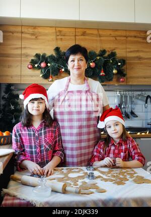 Oma und zwei Enkelinnen kochen Kekse in der Küche. Stockfoto