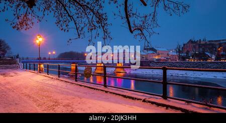 uzhhorod, ukraine - 26 DEC, 2016: Altstadt in einer weihnachtsnacht. Schöne Stadtlandschaft am Fluss. Schnee am Ufer. Brücke und Laternen glühen Stockfoto