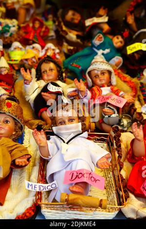 14. Dezember 2020, LA PAZ, BOLIVIEN: Jesuskind (auf Spanisch Niño genannt), als Arzt gekleidet und mit einer chirurgischen Gesichtsmaske als Schutz vor dem covid 19 Coronavirus, der auf einem Weihnachtsmarkt verkauft wird. Krippenbilder sind eine wichtige Weihnachtsdekoration in Häusern und öffentlichen Plätzen in Lateinamerika und auch in Spanien (wo die Tradition herkommt). Auf den Weihnachtsmärkten werden zahlreiche Figuren für Krippen verkauft; niños der Schutz vor dem covid 19 Coronavirus ist in diesem Jahr neben traditionell gekleideten niños als Folge der Pandemie eine neue Option. Stockfoto