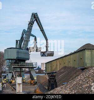 Großer Bagger arbeitet durch den Umgang mit Kieselsteinen aus dem Haufen von Steinen zu Container. Arbeitsmaschine auf der Baustelle. Branche. Stockfoto