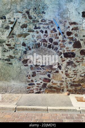 former arched gate in a house wall made of rubble stones Stock Photo