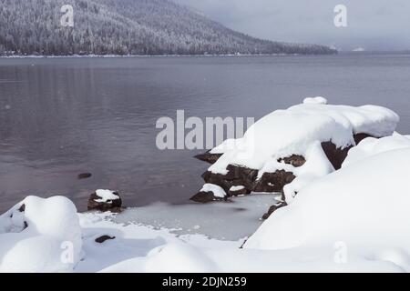 Große Felsen bedeckt mit Schnee am Mountain Lake im Winter Stockfoto