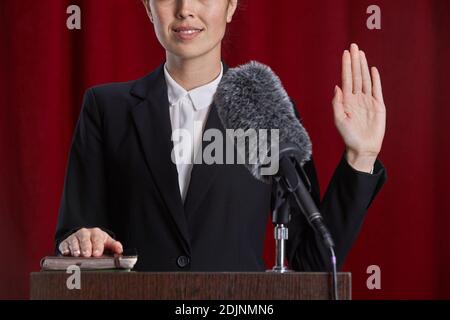 Nahaufnahme einer jungen Frau, die Eid ablegte, während sie auf dem Podium auf der Bühne gegen den roten Vorhang stand, Platz kopieren Stockfoto