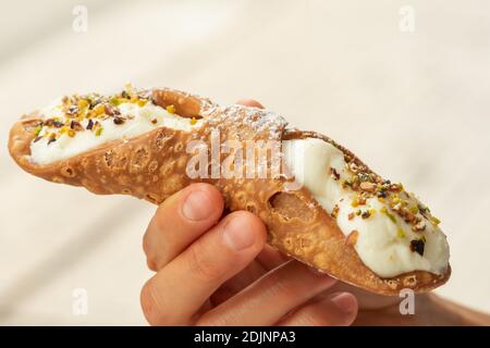 Nahaufnahme einer frischen sizilianischen Cannoli, von Hand gehalten. . Stockfoto