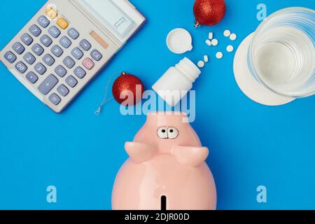 Flach legen mit weihnachtskugel, Pillen, Sparschwein, Glas Wasser und Rechner auf blauem Hintergrund. Stockfoto