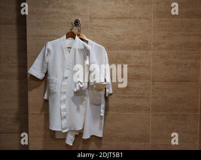 Weiße Frotteebademäntel an der Badezimmerwand. Bademantel nach dem Baden. Stockfoto