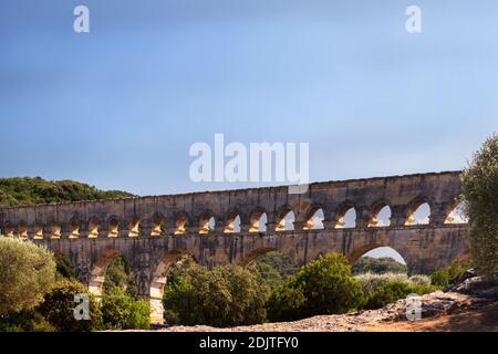 Die Pont du Gard vom Ufer des Flusses Gardon aus an einem schönen Sommernachmittag, Südfrankreich, gesehen Stockfoto