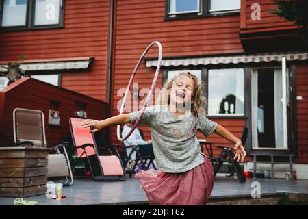 Nettes Mädchen mit Spaß mit Hula Hoop im Hinterhof mit Rotes Holzhaus Stockfoto
