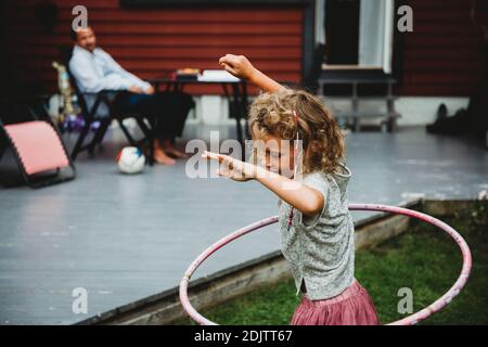 Seitenansicht von niedlichen Mädchen spielen mit Hula Hoop in Sommer im Hinterhof Stockfoto