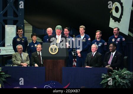 US-Präsident Bill Clinton (am Rednerpult) Adressen Mitarbeiter bei der NASA Johnson Space Center (JSC) während einer 14. April 1998 Besuch der Houston-Anlage. Sitzt hinter ihm (v.l.) sind JSC Direktor George W.S. Abbey, US-amerikanischer Jurist und Nick Lampson (Demokrat von Texas), NASA-Administrator Daniel Goldin und Houston Bürgermeister Lee Brown. Stehen Mitglieder der Besatzung von STS-95: (v.l.) Pedro Duque, Chiaki Mukai, US-Senator John H. Glenn Jr. (Demokrat of Ohio), Stephen K. Robinson, Scott E. Parazynski, Steven W. Lindsey und Curtis L. Brown Jr. Brown ist Kommandant der Schedu Stockfoto